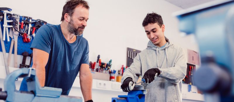 Metallwerkstatt mit Jugendlichem und Betreuer